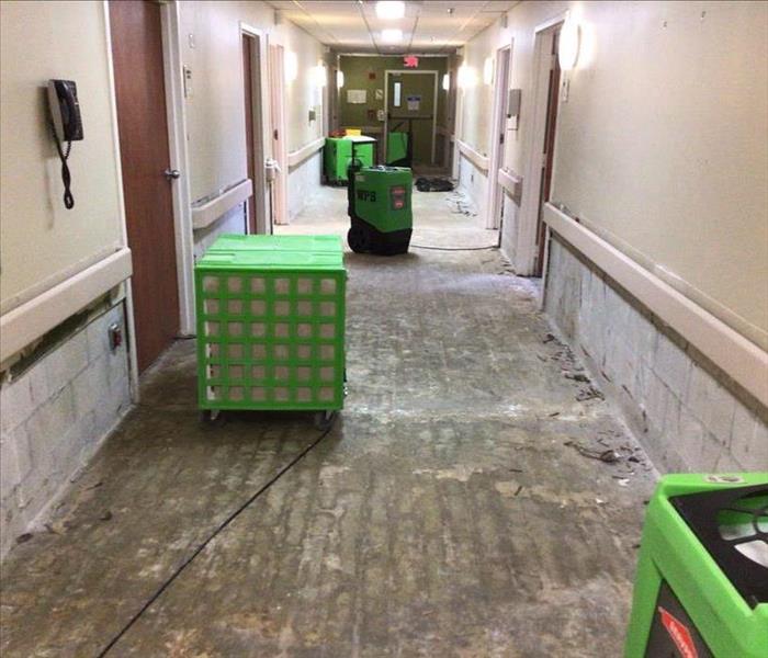 medical facility hallway post demolition with no drywall or flooring and green equipment set up