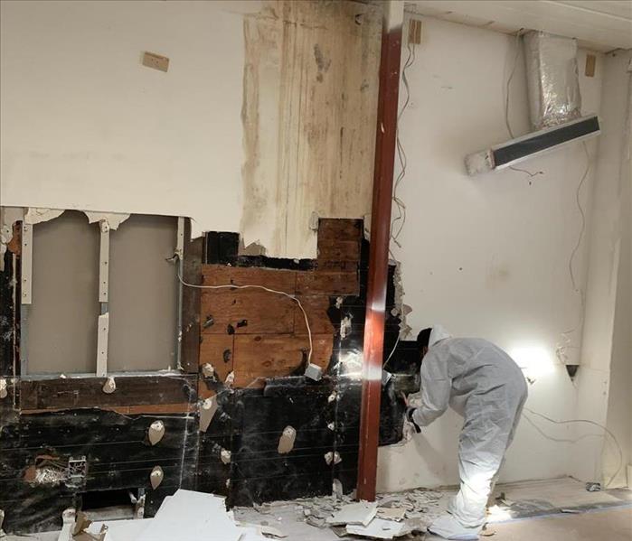 Cleaning crew member performing restoration to a wall destroyed by water and mold damage. 